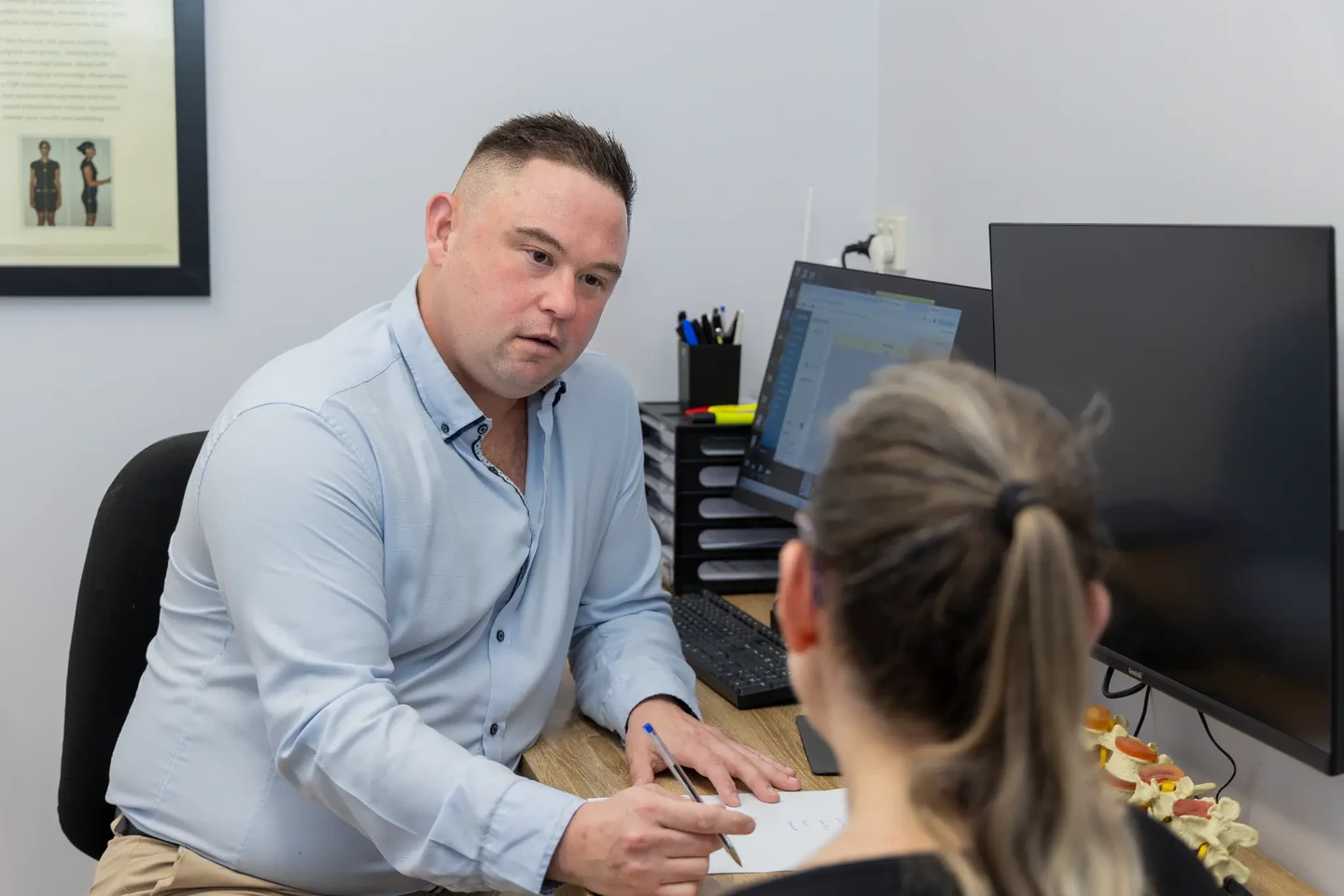 Dr Michael listening during an office consultation with a female patient at Charlton Chiropractic Redbank